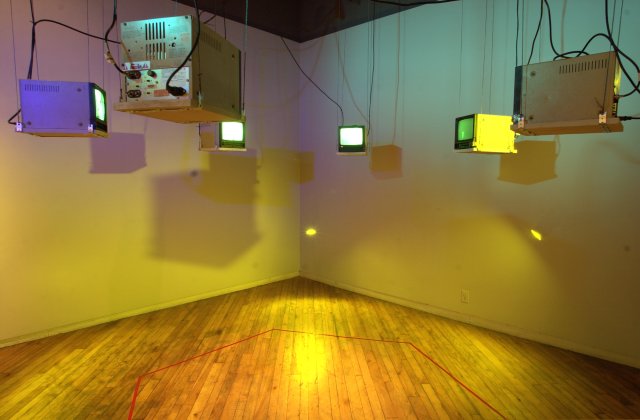 Six television receivers hanging from the ceiling in a hexagonal
          arrangement, providing video output from the six decon rooms.
